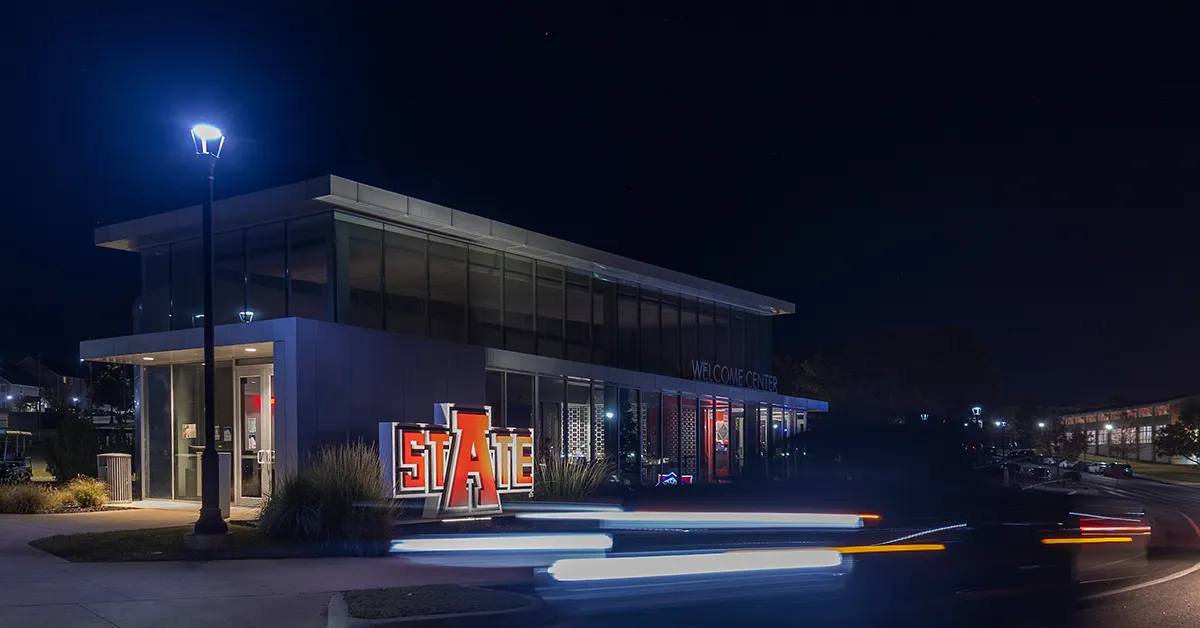 The A-State Welcome Center illuminated at night on campus.