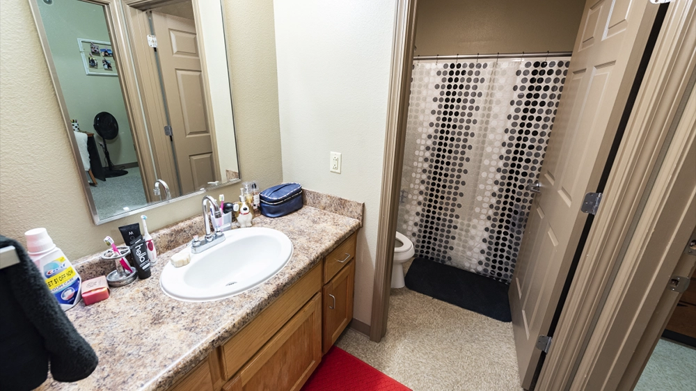 Bathroom with sink and doorway to shower and toilet area.