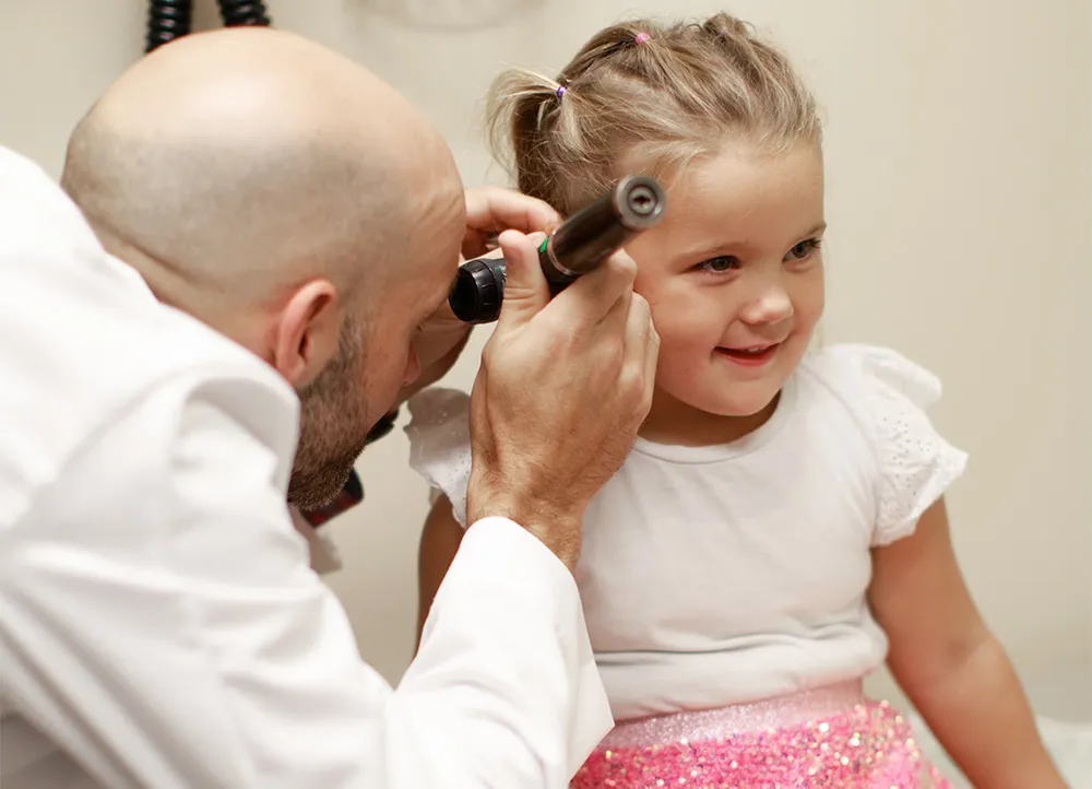 doctor examing a smiling young girl's ear