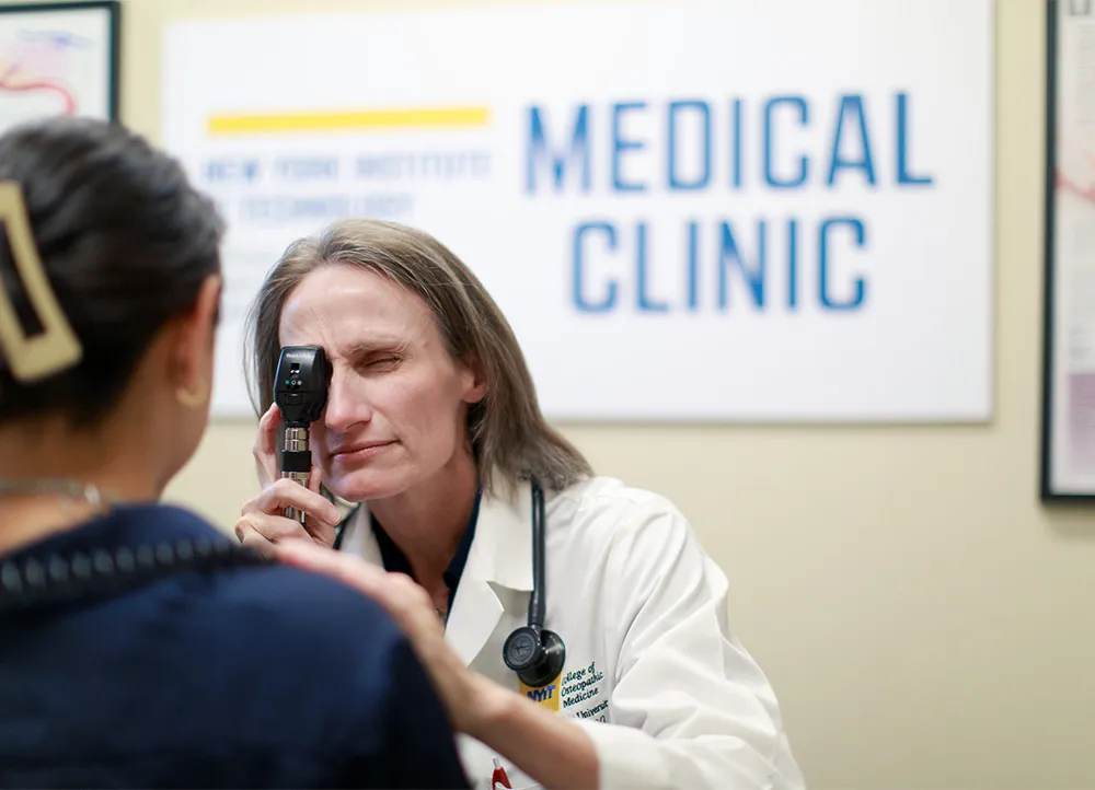 a doctor peers through instrument while examing patient