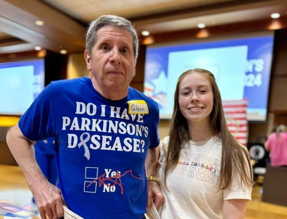 A-State occupational therapy student standing with patient wearing a funny parkinson's disease shirt..