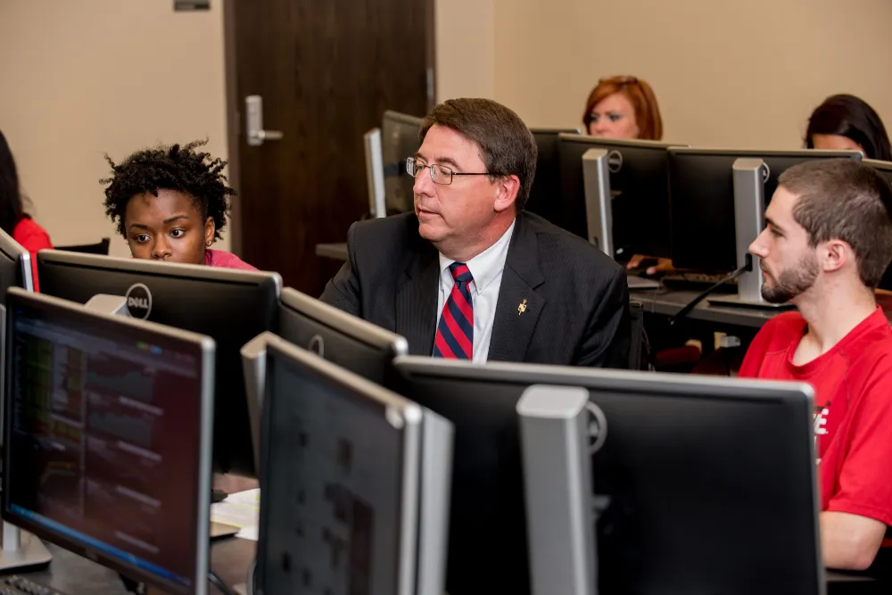 Accounting student and professor sitting at table with A-State hoodie and laptop