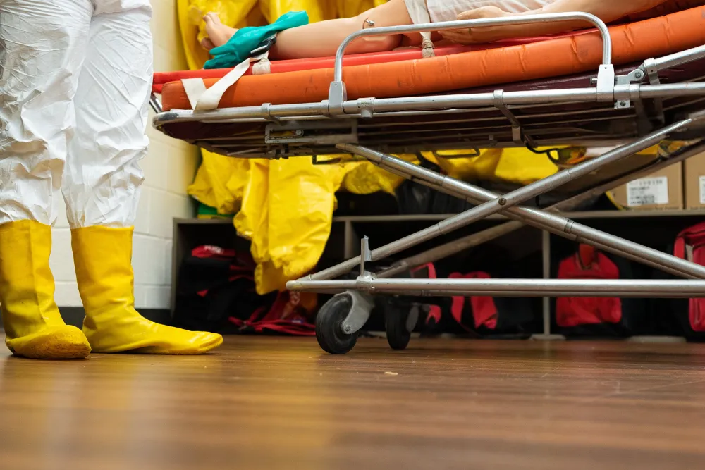 Disaster Preparedness and Emergency Management student standing over a stretcher with a dummy on it.