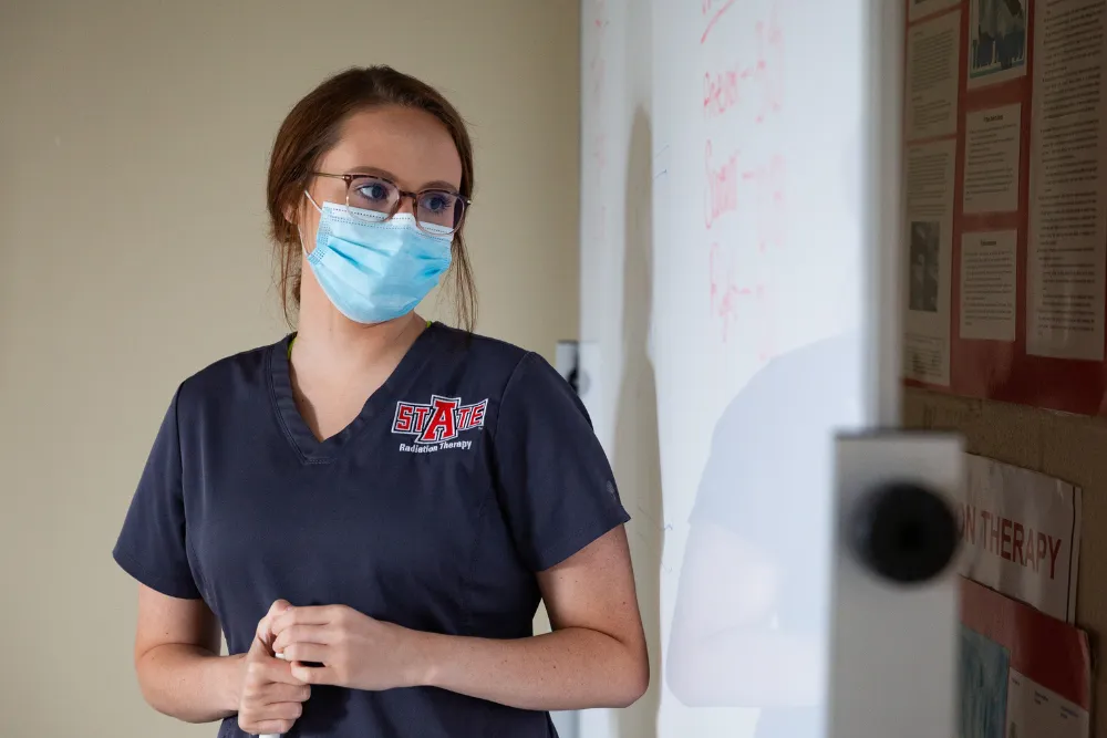 Radiation Therapy student in front of whiteboard going over the class lecture.