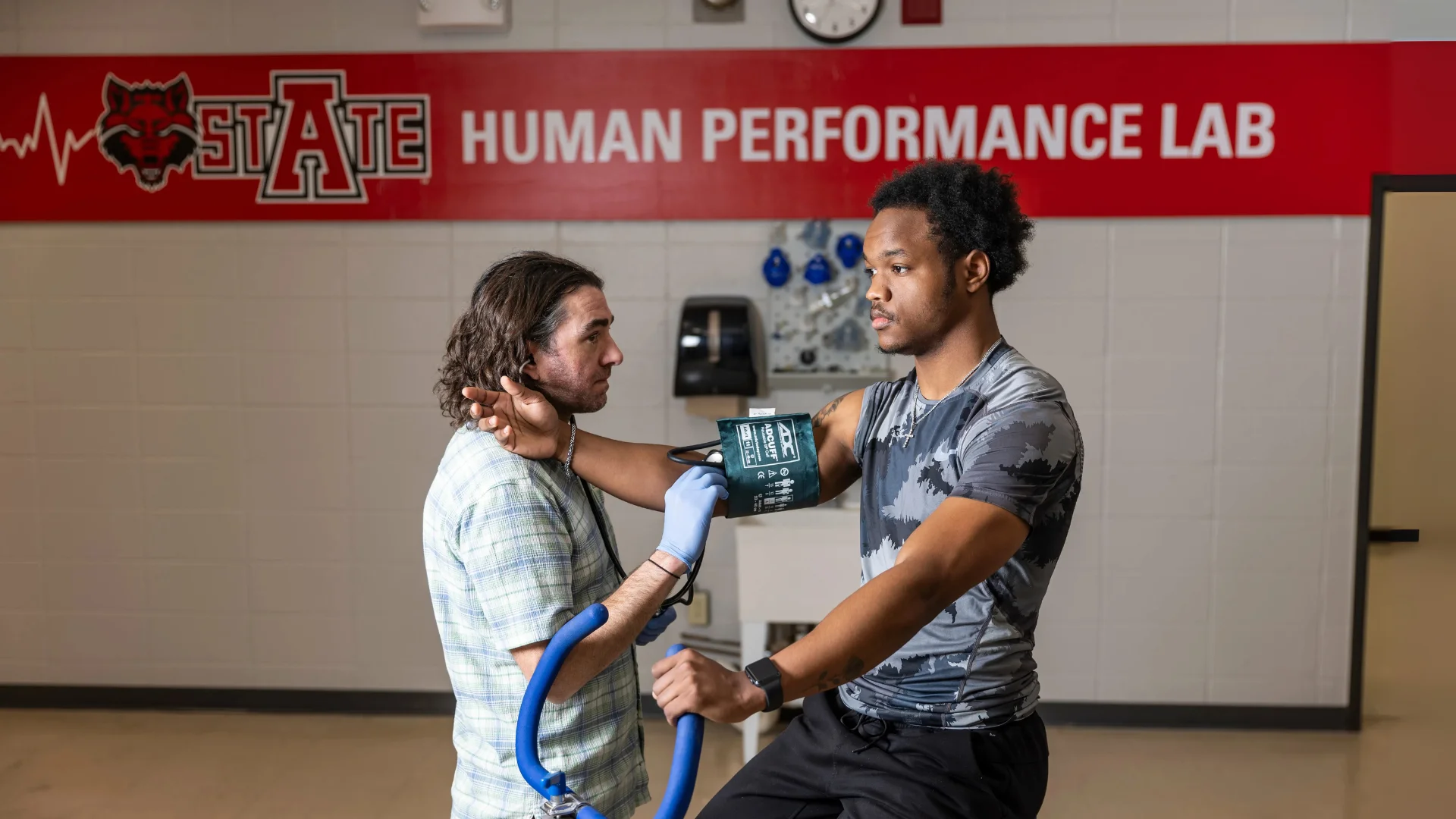 A professor monitoring the heartrate of an exercising student.