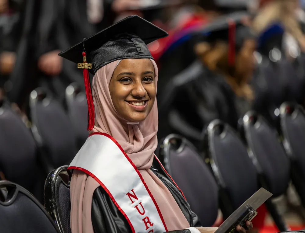 Nursing student at graduation with a nursing sash, smiling.