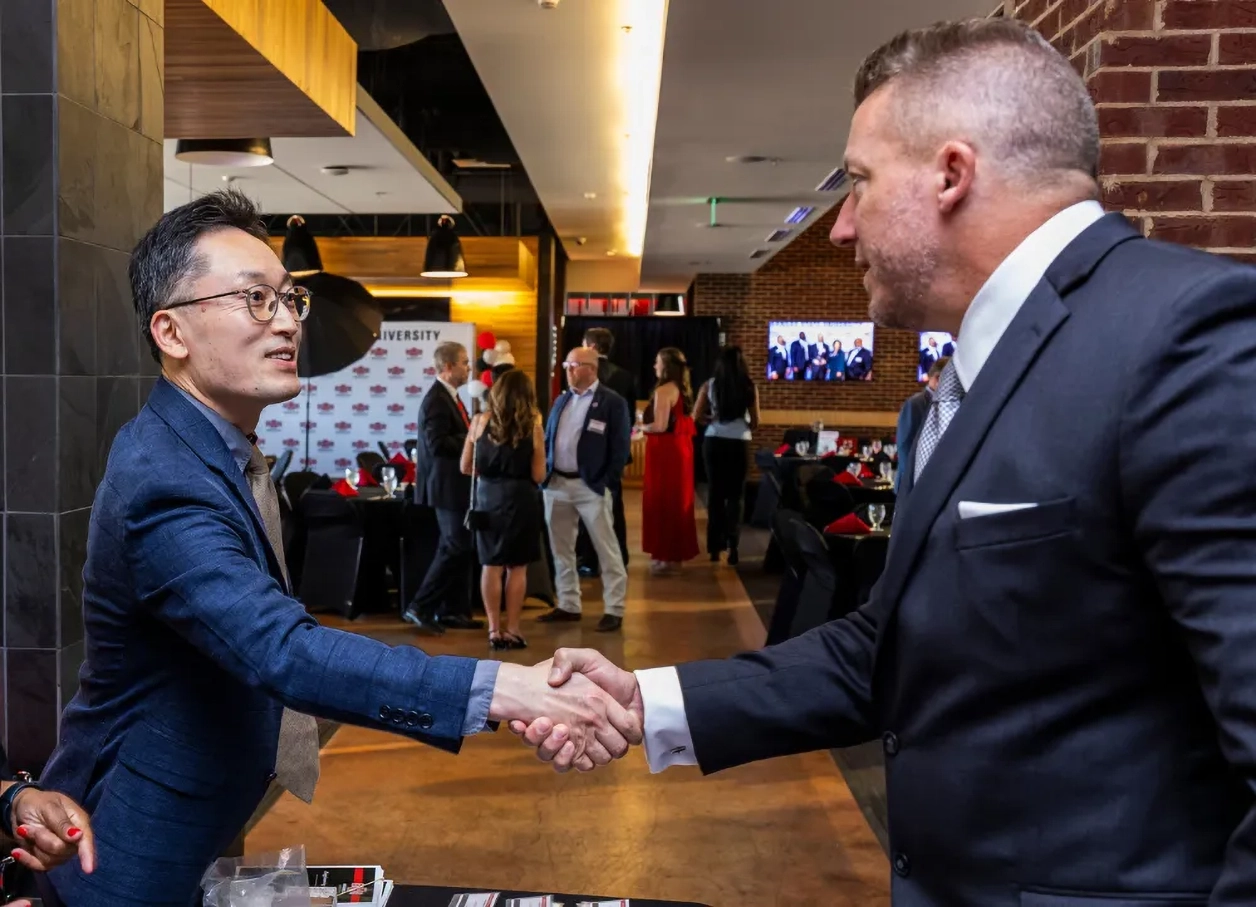 Dr. Hwang shaking hands with alumni.