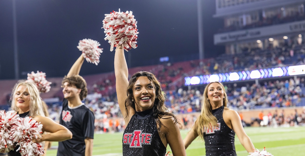 Spirit squad students cheer at football game.