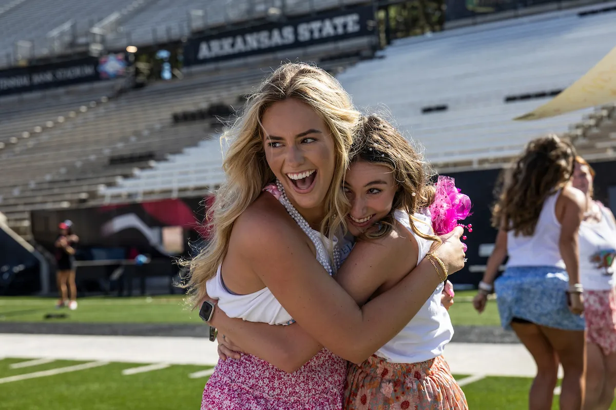 Two sorority members hug at a new member reveal event.