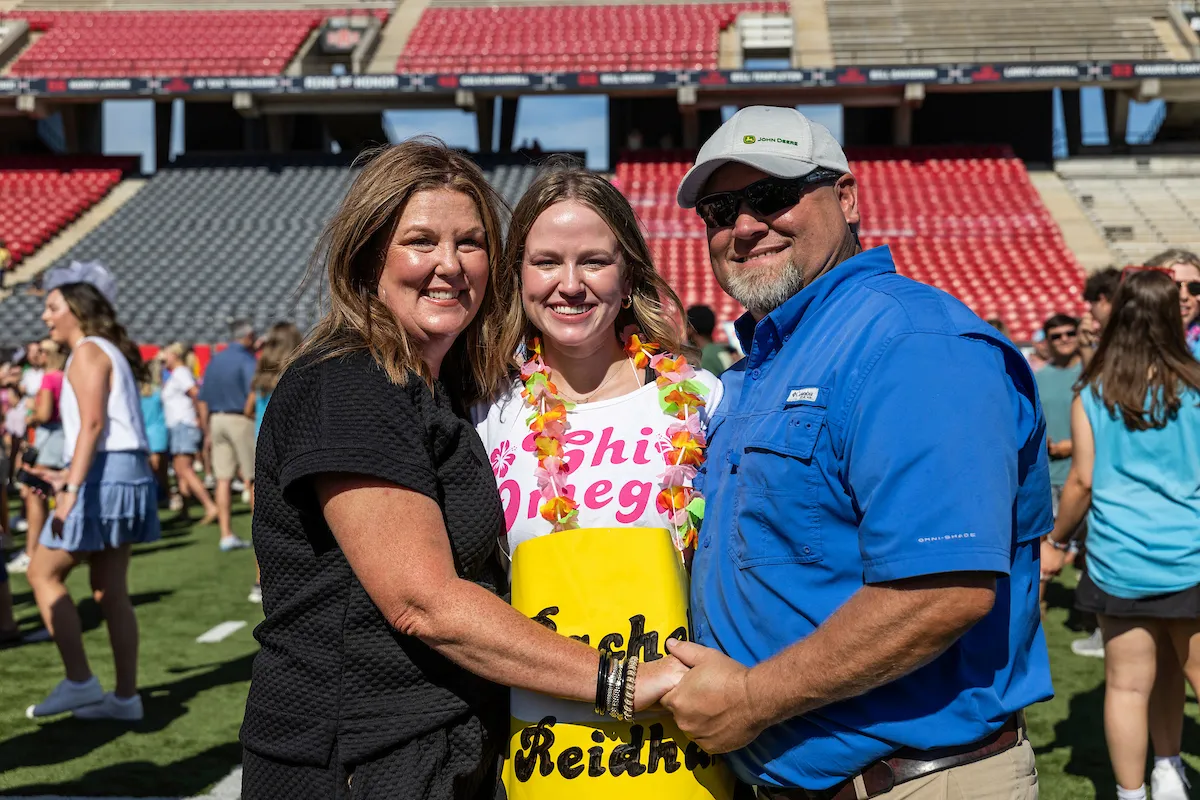 A sorority recruit poses with her family at the reveal event.
