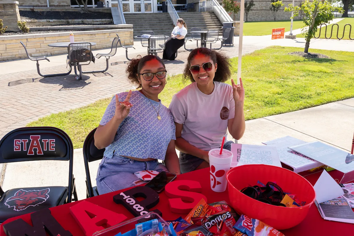 Two MC ambassadors work an information desk at a university event.