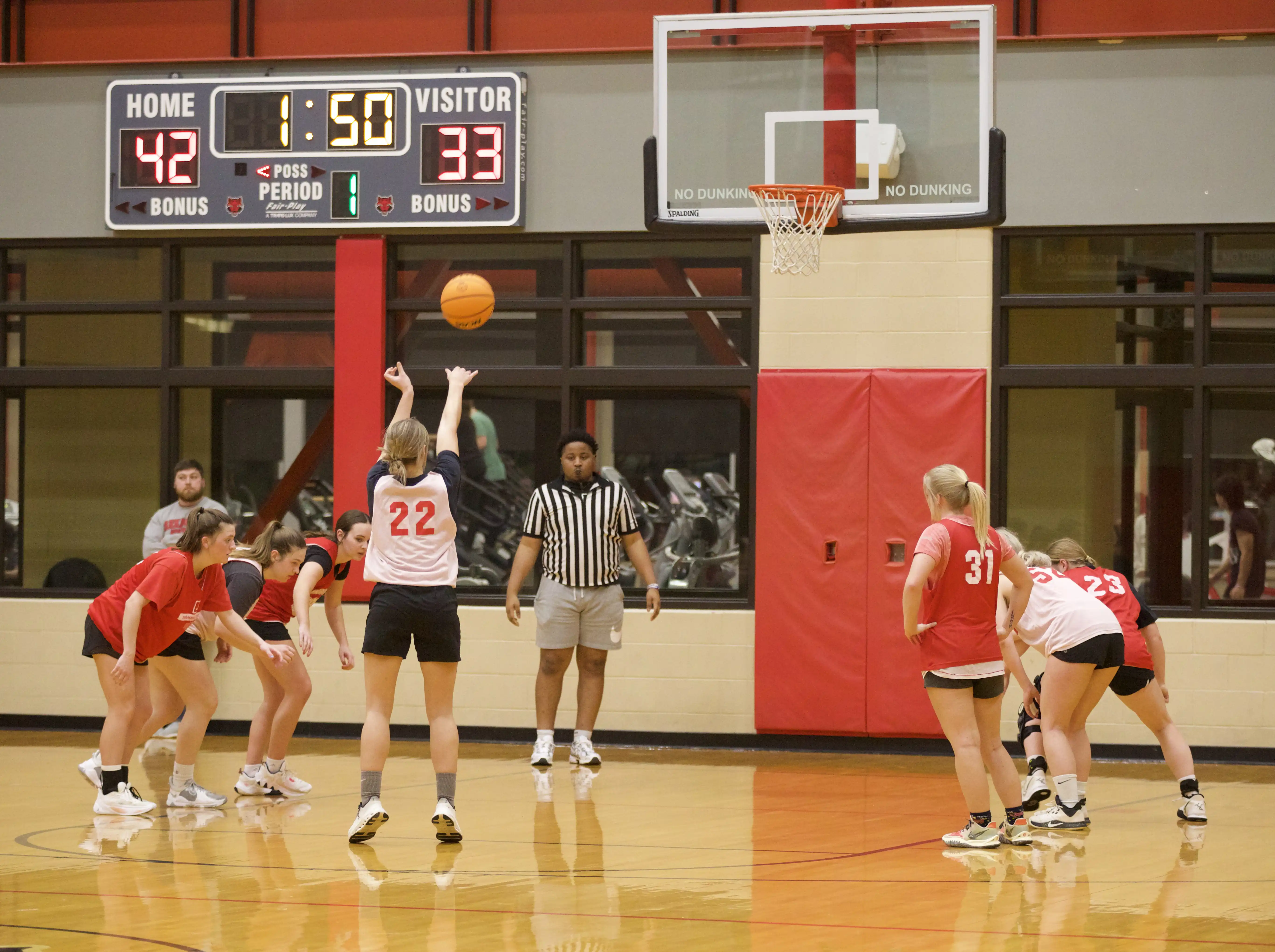 Students on gym floor playing basketball.