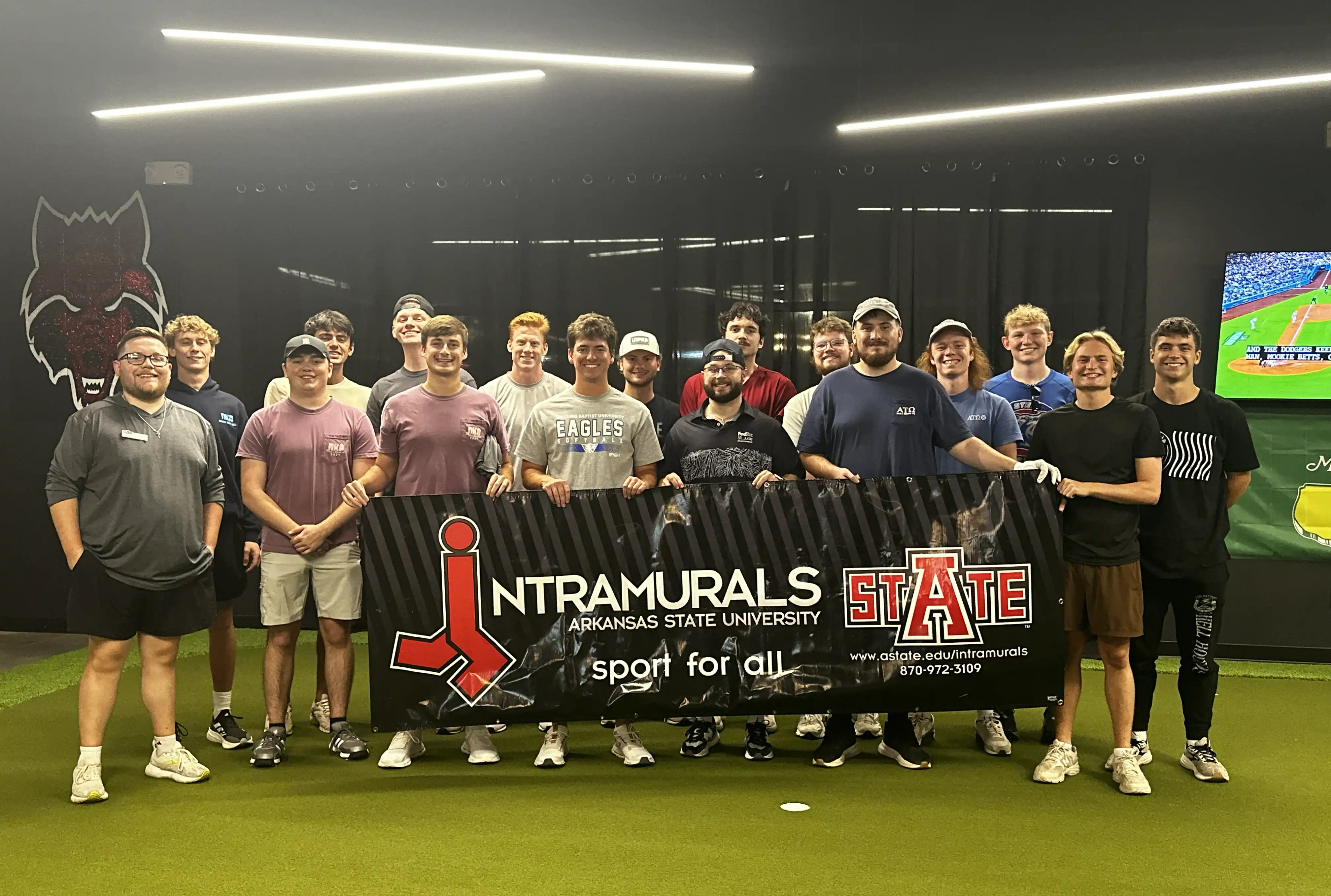 Students posing behind Intramural champion banner at golf tournament.