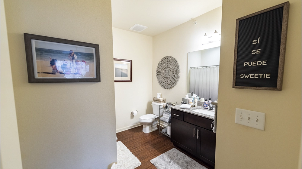 Bathroom with granite vanity, large mirror, and decorative wall art.