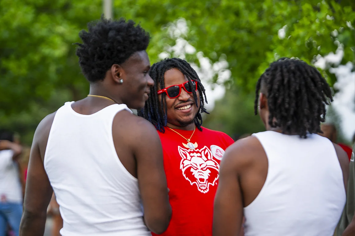 A student in Red Wolves gear smiling with two friends.