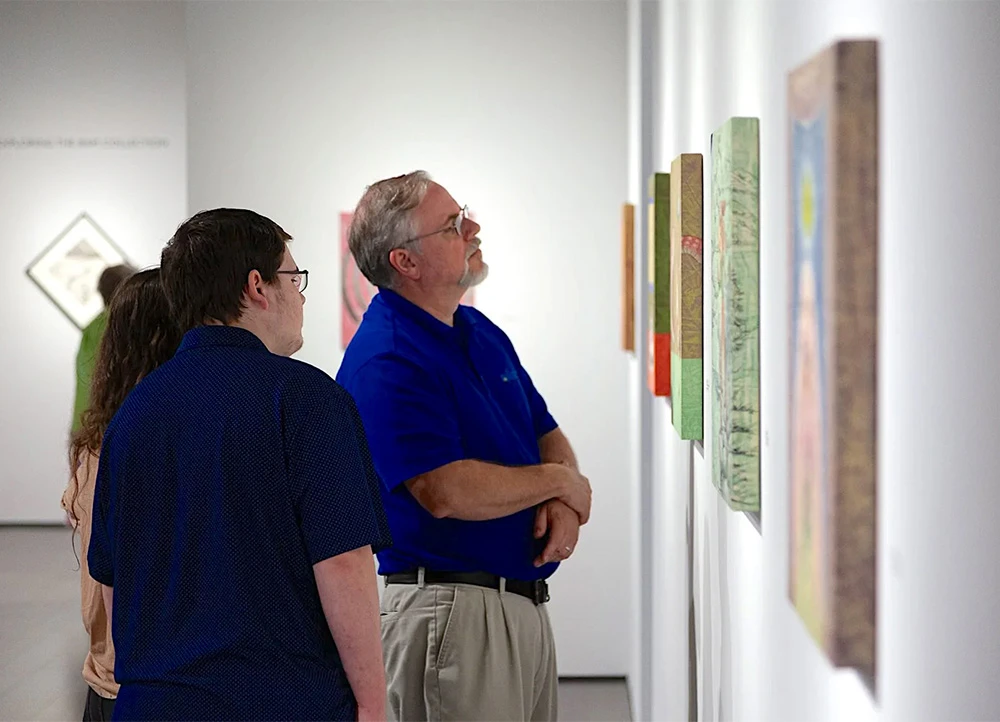 people intensely studying paintings in an art gallery