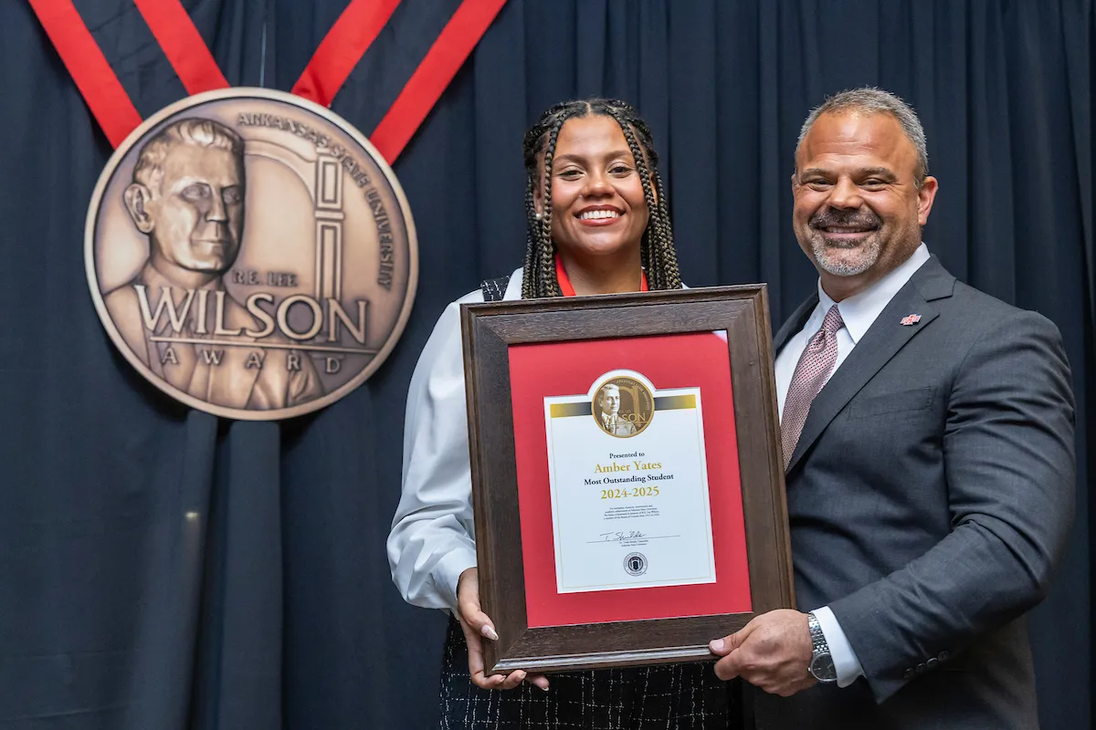Chancellor Todd Shields presents the 2025 Wilson Award to Amber Yates.  The Wilson Award is the highest student award given at A-State.