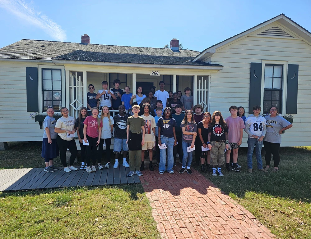 Students posing for a picture outside of the Johnny Cash Boyhood Home.