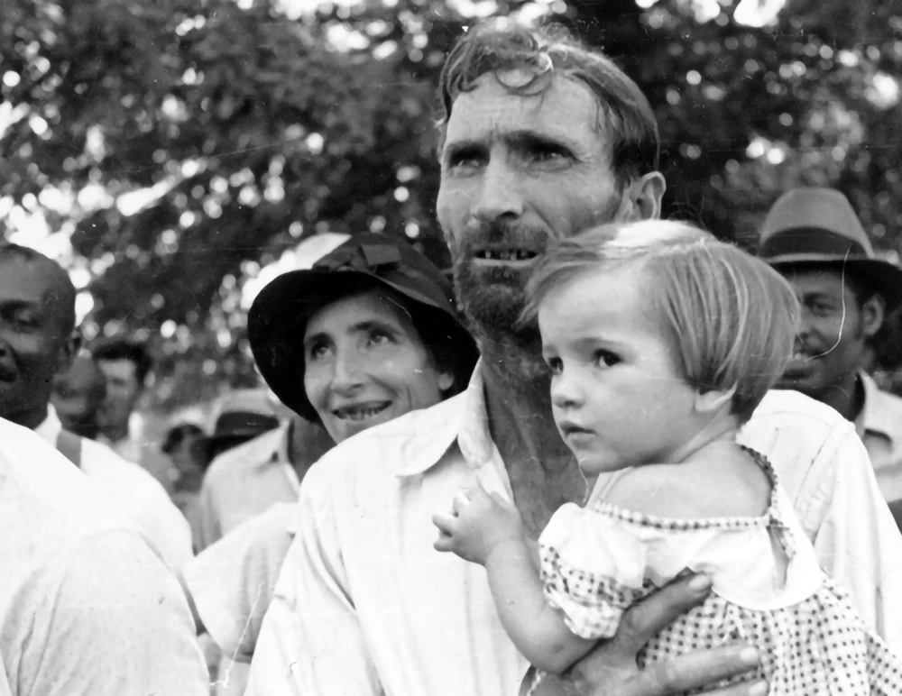 Black and white photo of man holding child at Southern Tenant Farmers Union meeting.