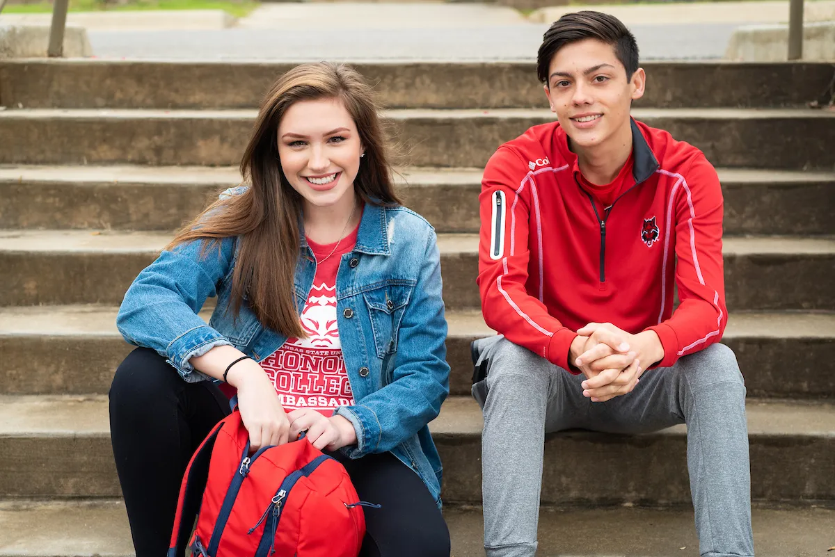 Students sitting in front of a residence hall on campus