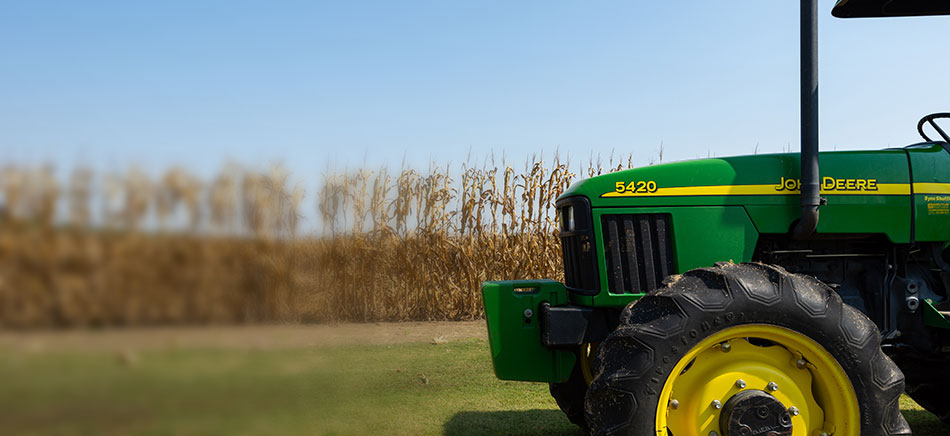 A John Deere tractor parked next to a field
