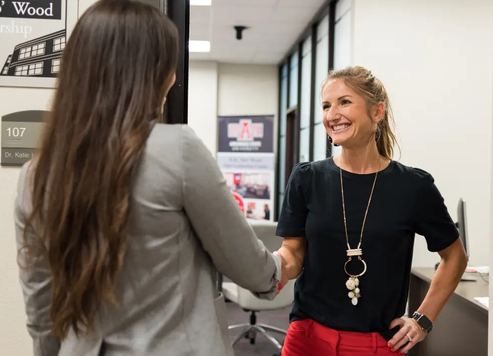Dr. Hill shaking a students hand in the sale leadership center.