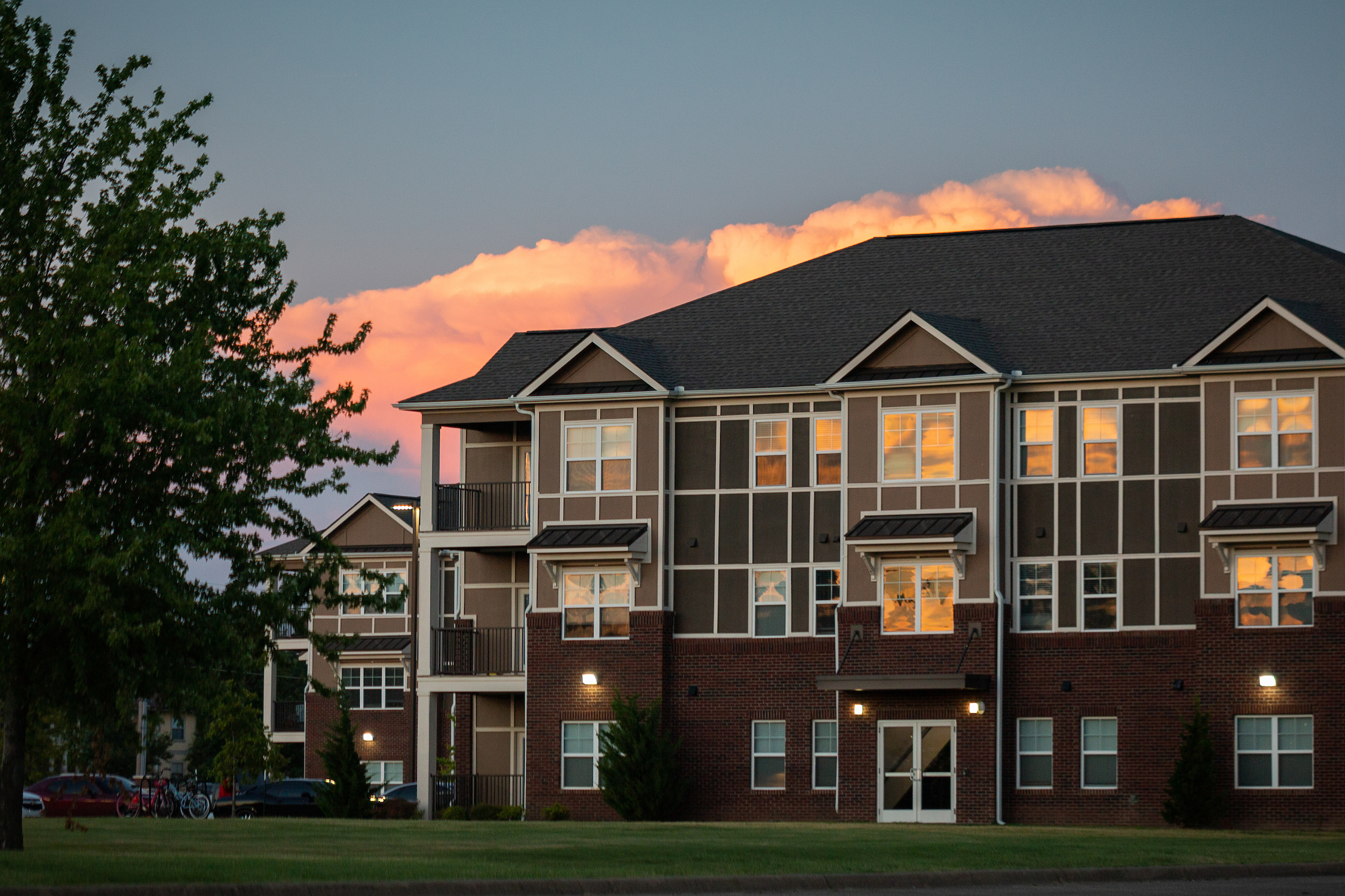 Sunset reflects off A-State campus housing with warm light glowing in the apartment windows.