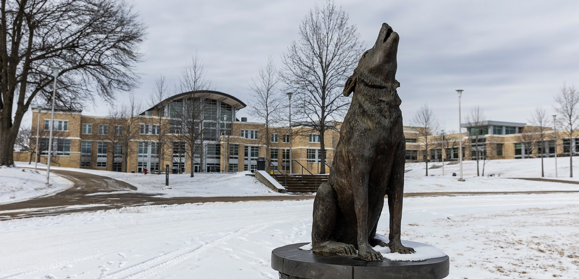 The howl statue stands outside of the student union with snow covering the grounds.